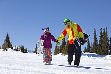 USA, Colorado, Telluride, Father and daughter (10-11) walking with snowboards in winter scenery