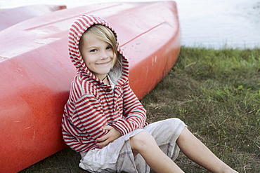 Portrait of boy (4-5) sitting by canoe