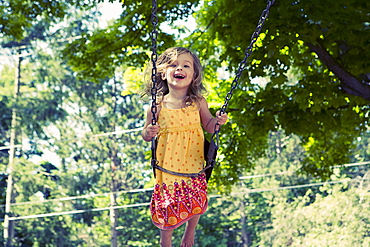 Girl (2-3) on swing in playground