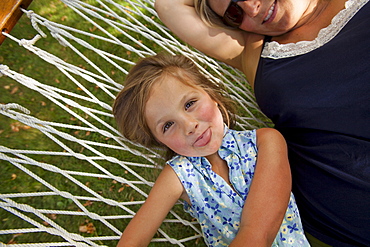 Portrait of girl (4-5) with mother in hammock