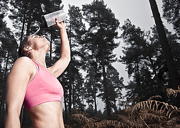 England, Suffolk, Female athlete pouring water on head, Thetford Forest