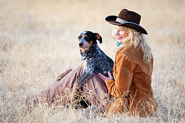 Woman and dog sitting in field