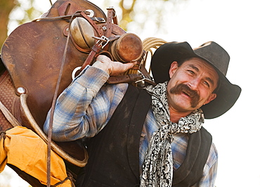 Cowboy holding saddle