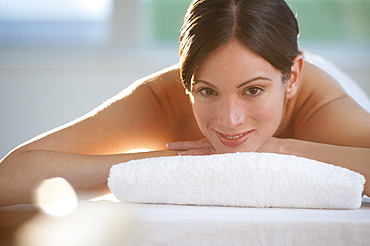 Mid-adult woman lying on massage table with candle in foreground