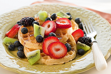 Waffles with berries and kiwi on plate