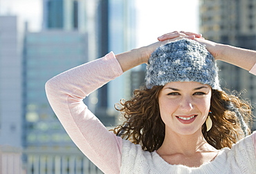 Portrait of woman in stocking cap with city in background