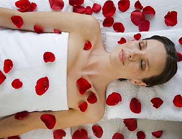 Woman covered in flower petals laying on massage table