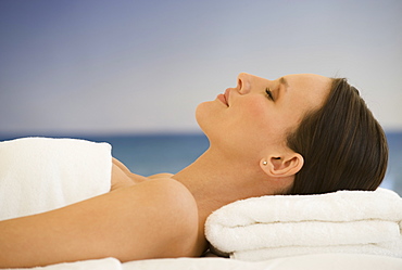 Woman laying on massage table with ocean in background