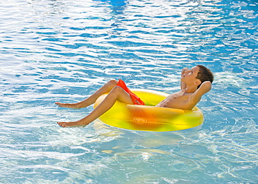 Boy relaxing in inflatable tube in swimming pool