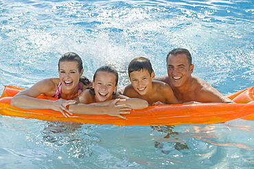 Family resting on raft in swimming pool