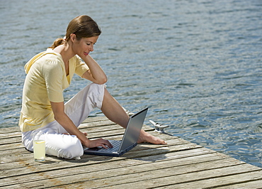 Woman using laptop on dock