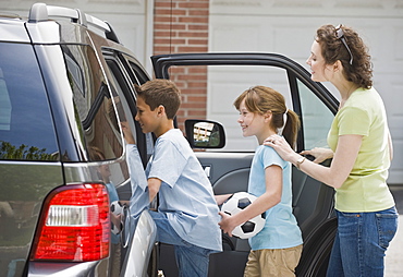 Mother and children getting into car with soccer ball