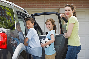 Mother and children getting into car with soccer ball