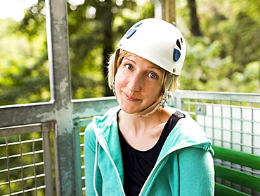 Woman in protective helmet and sitting at net elevator looking at camera, Costa Rica