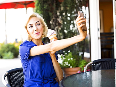 Woman photographing herself with ice-cream, Costa Mesa, California