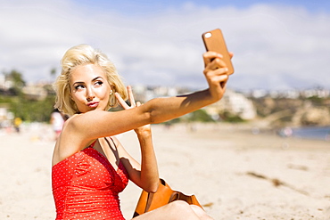 Blond woman taking selfie on beach, Costa Mesa, California