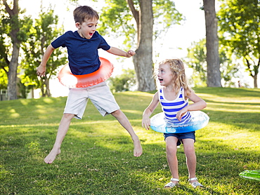 Two kids (4-5, 6-7) playing with inflatable rings in park, USA, Utah, Salt Lake City 