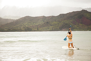 Woman paddling on shallow water, Kauai, Hawaii