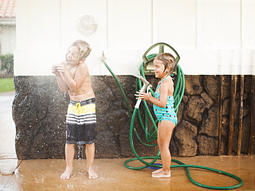 Children (2-3, 6-7) refreshing with garden hose