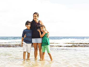 Portrait of girl (6-7) and boy (10-11) standing on beach with mother, Kauai, Hawaii