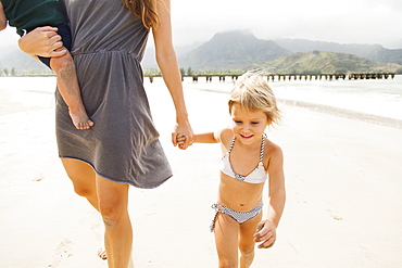 Mother walking with daughters (6-11 months, 2-3) on beach, Kauai, Hawaii