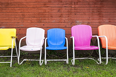 Colorful plastic chairs in row against red wall, Hood River, Oregon