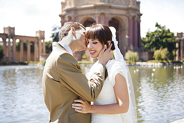 Groom kissing bride in park, San Francisco, California