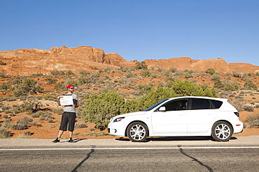 USA, Utah, Moab, Man standing beside car reading map, USA, Utah, Moab