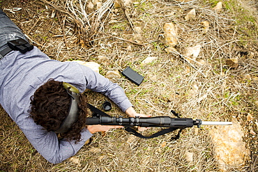 Man lying on front with weapon