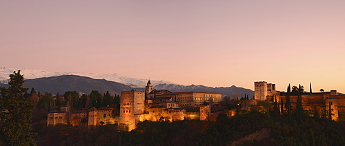 Cityscape with illuminated castle at dusk, pink sky, Alhambra, Granada, Spain 