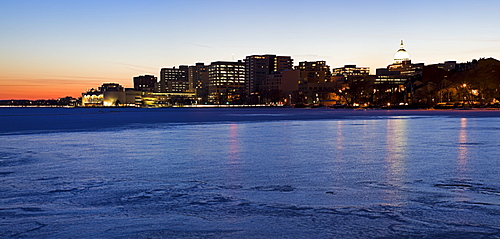 USA, Wisconsin, Madison skyline across frozen lake at dusk