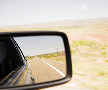 Road reflected in car side mirror