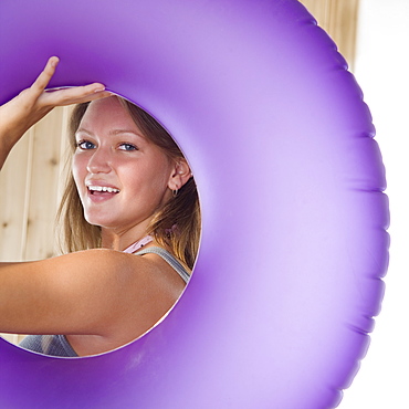 Young woman smiling through middle of inner tube