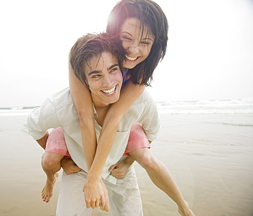 Man giving woman piggyback ride at beach