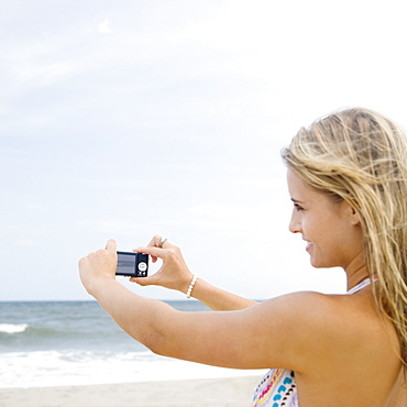 Woman taking photograph of ocean