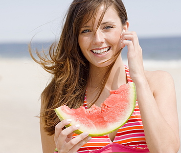 Woman eating watermelon at beach