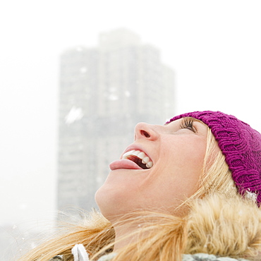 USA, New Jersey, Jersey City, woman catching snowflakes with tongue