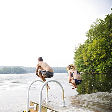 USA, New York, Putnam Valley, Roaring Brook Lake, Couple jumping from pier to lake