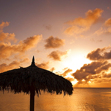 Aruba, silhouette of palapa on beach at sunset