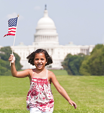 USA, Washington DC, girl (10-11) with US flag running in front of Capitol Building