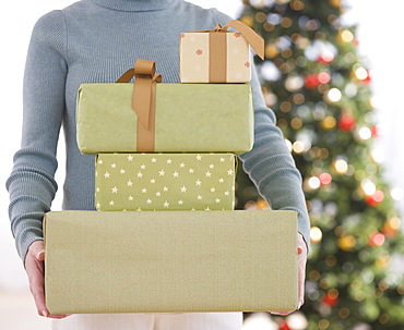 Woman holding stack of Christmas gifts