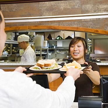 Customer receiving tray of food in bakery