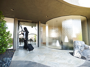 Woman leaving house with piece of luggage, USA, Utah, St George