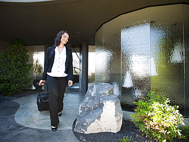 Woman leaving house with piece of luggage, USA, Utah, St George