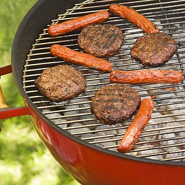 Hot dogs and hamburgers cooking on grill