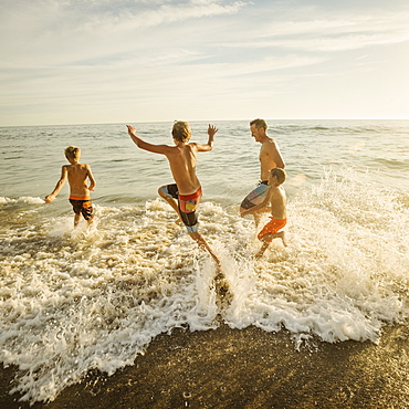 Father on beach with his three sons (6-7, 10-11, 14-15), Laguna Beach, California