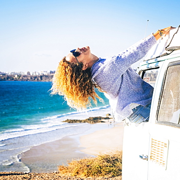 Woman leaning out of camper van window by beach in Fuerteventura, Canary Islands