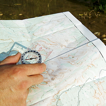 Hand holding a compass and map