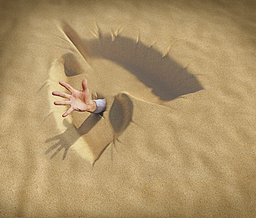 Hand reaching from lungs shaped sand