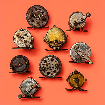 Antique fishing reels arranged on an orange background